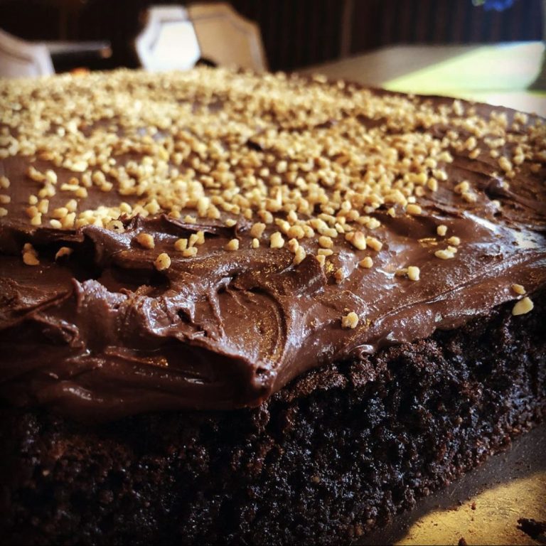 Hausgebackene Kuchen Schokoladenkuchen mit cremiger Glasur und einer Schicht aus goldenen Streuseln.