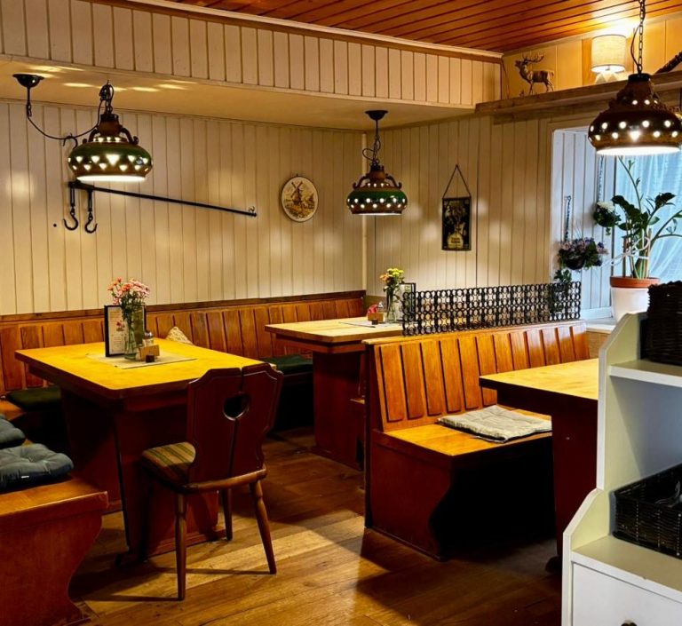 Vorderer Gastraum Gemütlicher Restaurantbereich mit Holztischen, Stühlen und stilvollen Lampen.